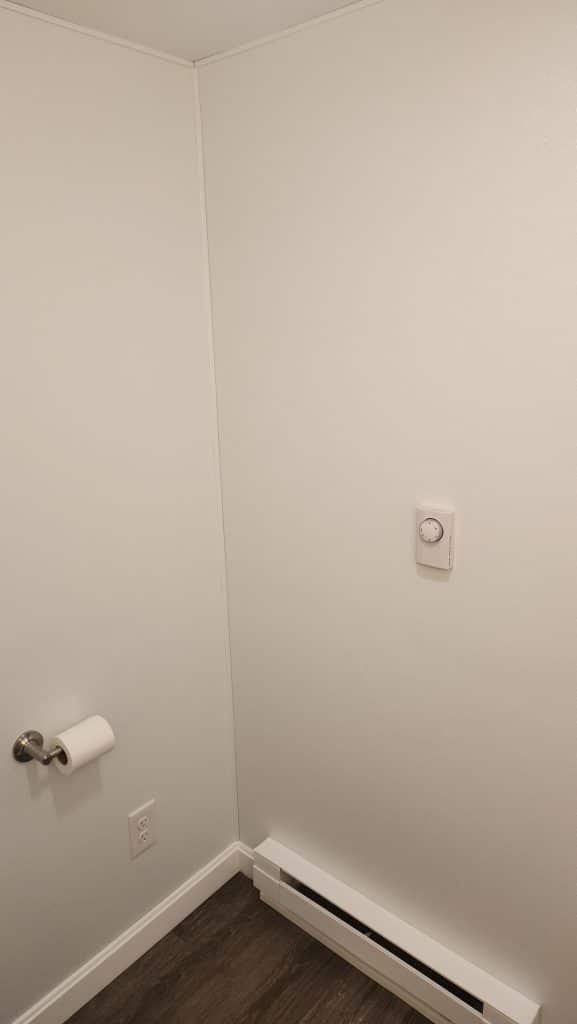 Electric baseboard heater with wall thermostat in a finished basement bathroom