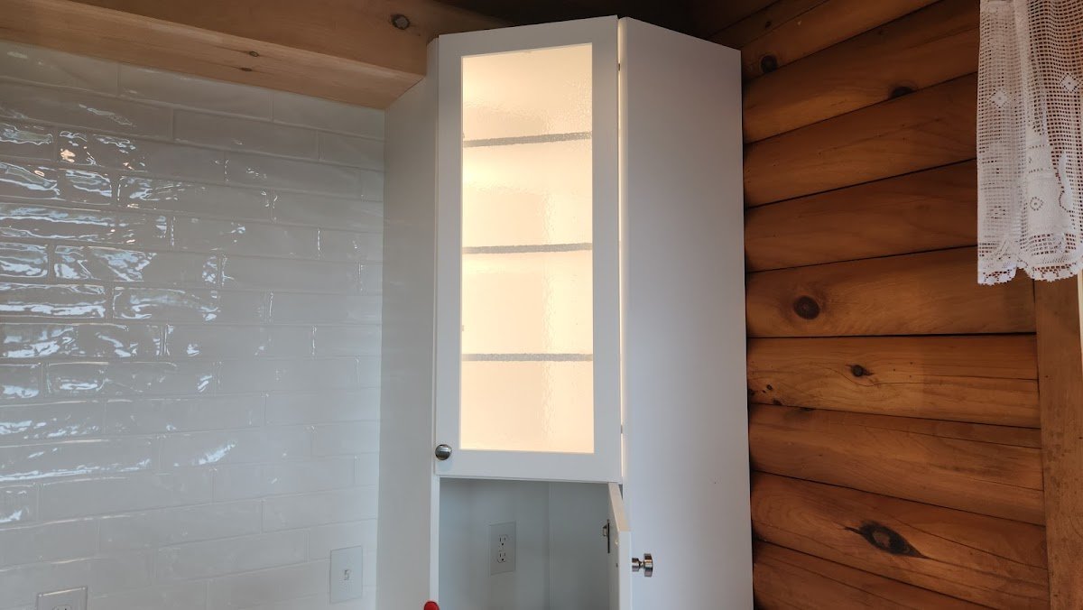 Lighted glass-front cabinet in a log home kitchen wired by Electric Wizard